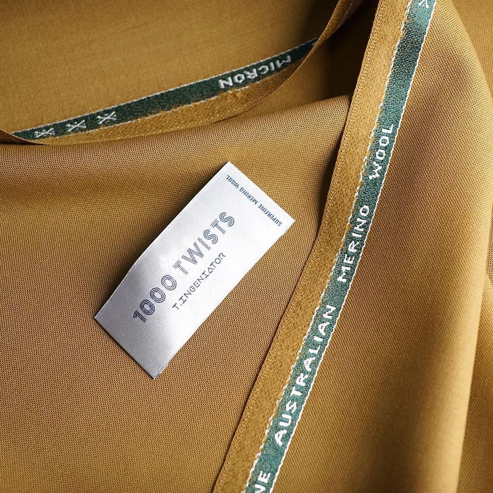 Ochre fabric with a visible woven edge and paper label